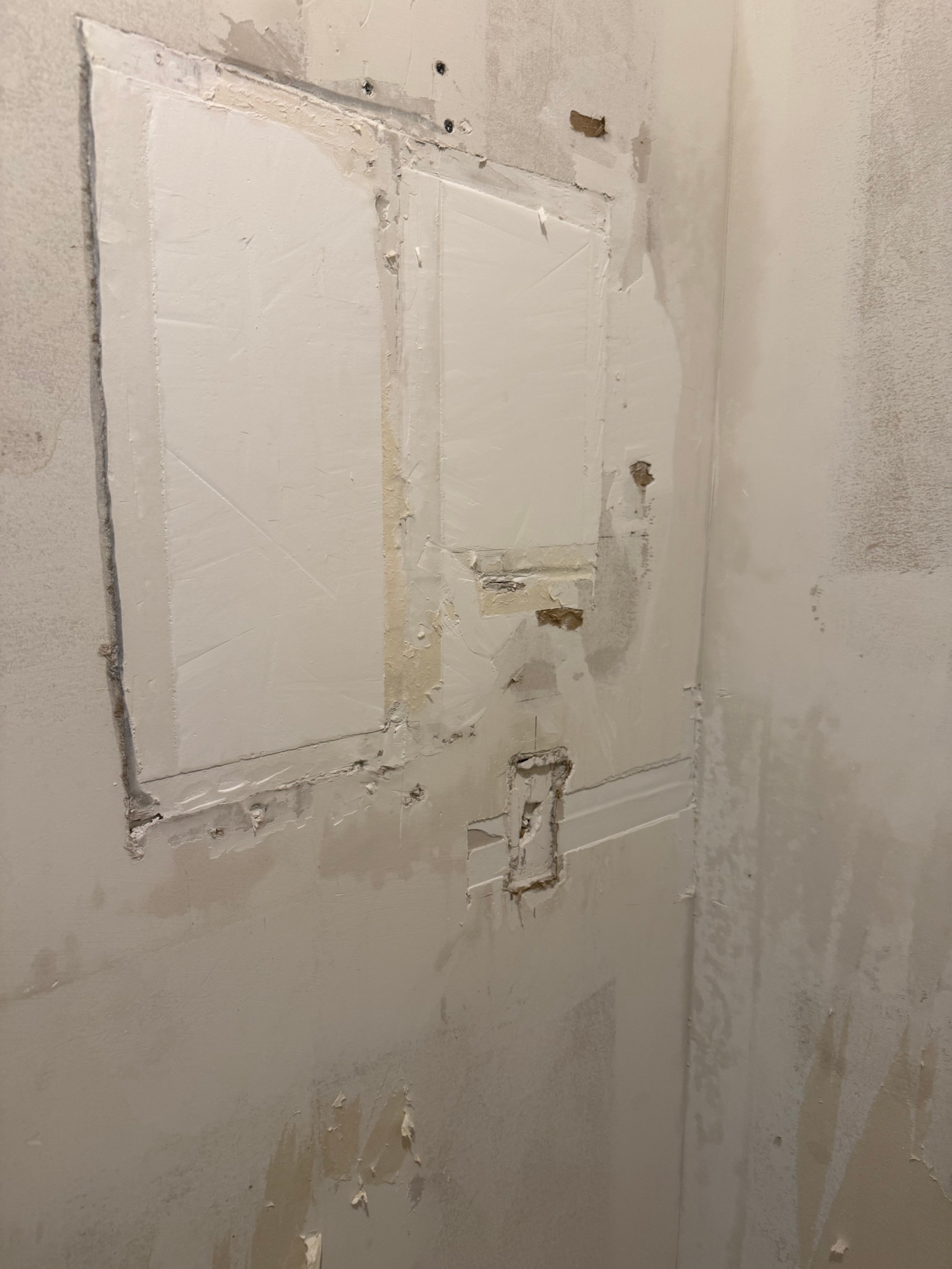 Smooth finish coat applied over patches, walls ready for paint