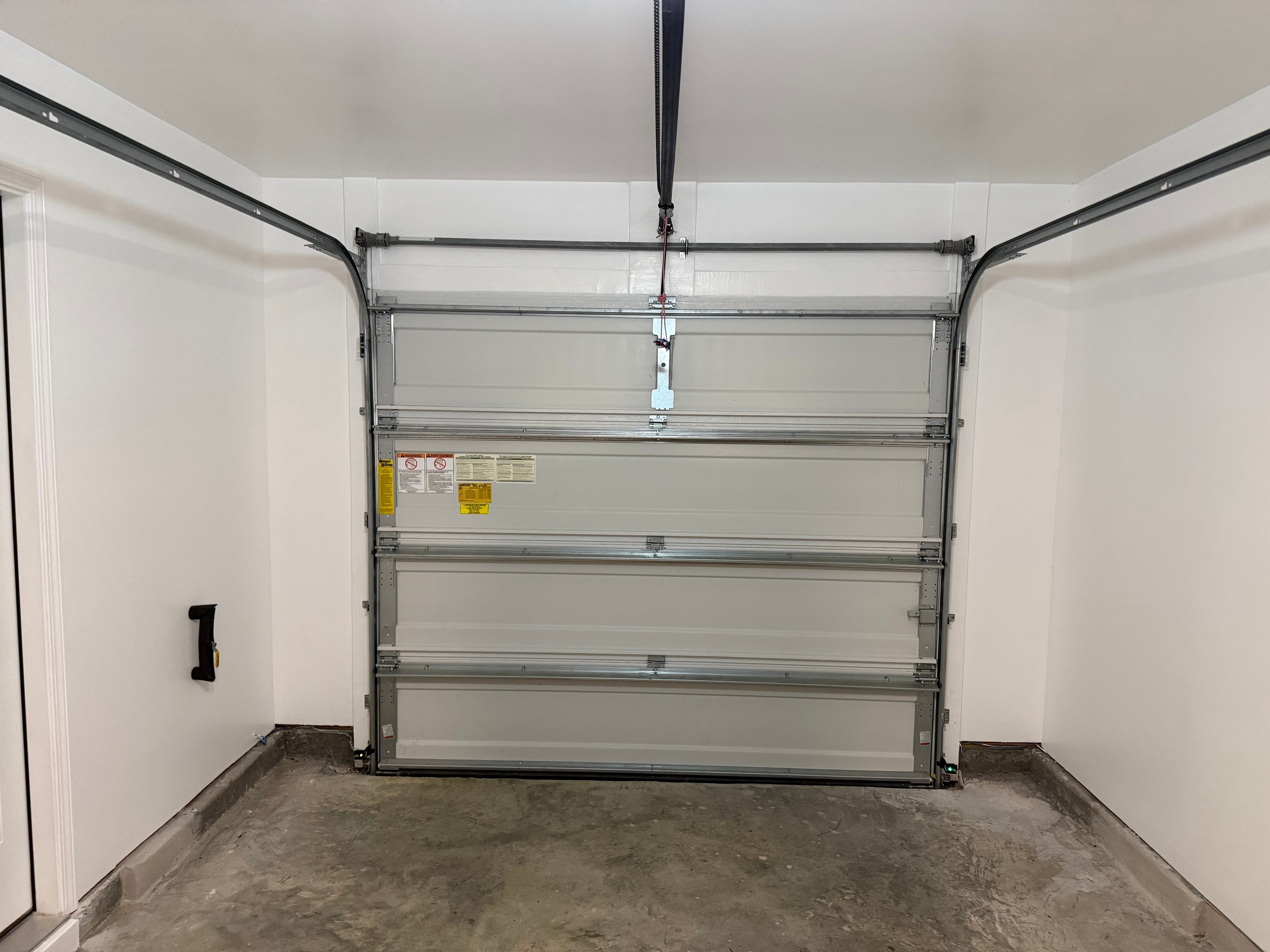 Unfinished garage with joint compound on drywall, door installed before paint