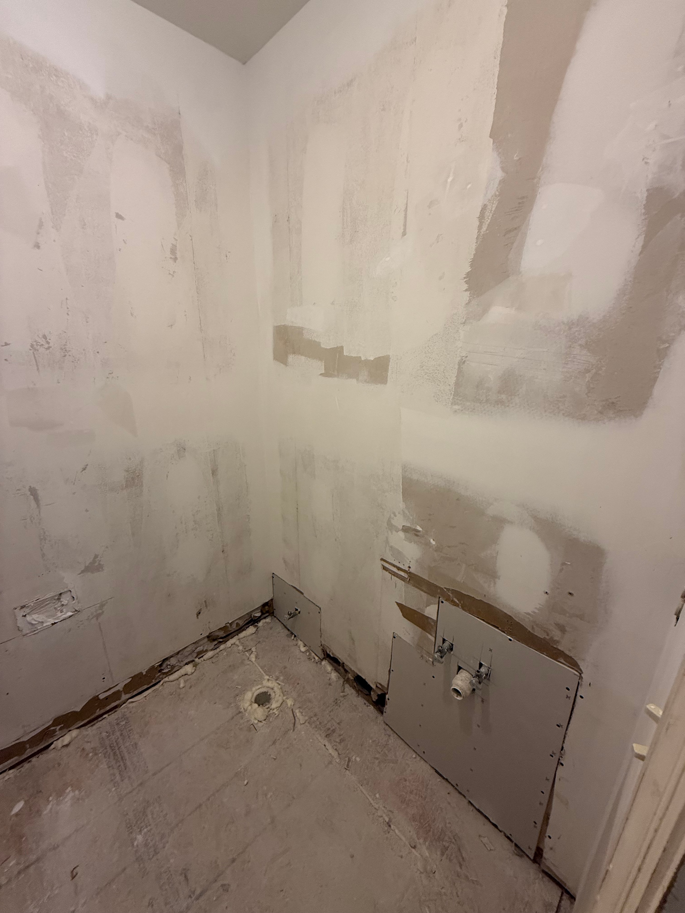 Wallpaper removed, drywall damage visible around old vanity plumbing